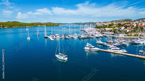 A yacht departs from the marina in Šibenik, Croatia, gliding through the calm waters of the Adriatic Sea. This aerial view captures the scenic coastline, with the historic city of Šibenik  photo