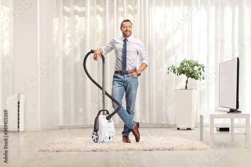 Man gesturing standing with a vacuum cleaner on a carpet