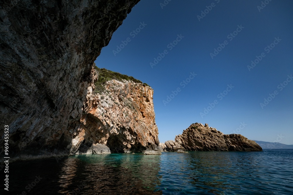 Fototapeta premium Coastal cliffs and the serene water of the Ionian sea under a blue sky in Zakynthos island, Greece