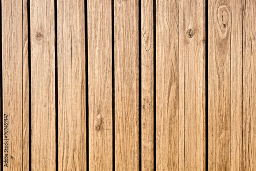 Close-up of a weathered, light brown wooden plank wall, featuring a vertical grain pattern, and knots.