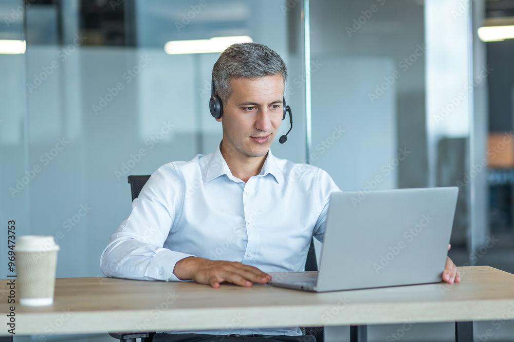 Professional Man Working at Laptop with Headset in Office