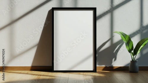 A modern interior showcasing a blank frame and a plant, enhanced by soft shadows on the wall, perfect for artistic displays.
