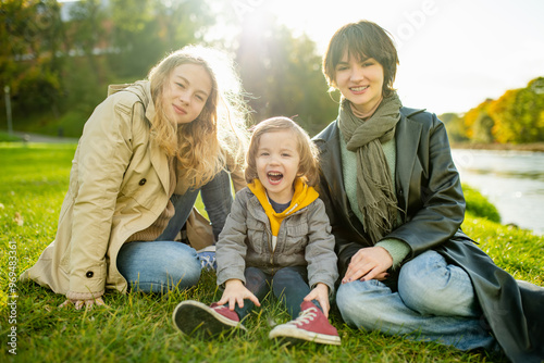 Two big sisters and their toddler brother having fun outdoors. Two young girls with a toddler boy on autumn day.