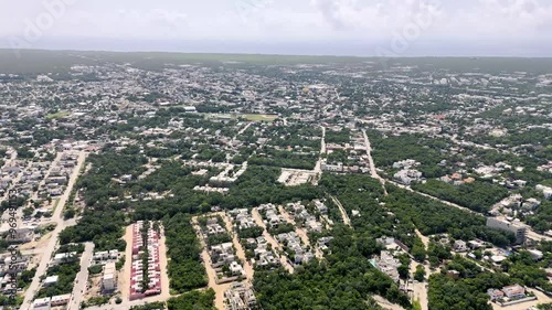 aerial drone view of downtown tulum with buildings and houses surrounded by green tropical areas and Caribbean Sea on the background on a cloudy morning in Mexico