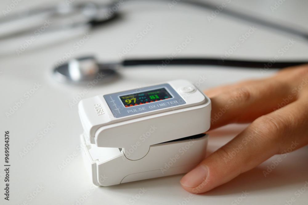 Unrecognizable woman monitoring blood oxygen level using digital fingertip oximeter to measure her pulse and saturation ensuring proper health care during routine medical checkup Unrecognizable woman monitoring blood oxygen level using digital fingertip oximeter to measure her pulse and saturation ensuring proper health care during routine medical checkup