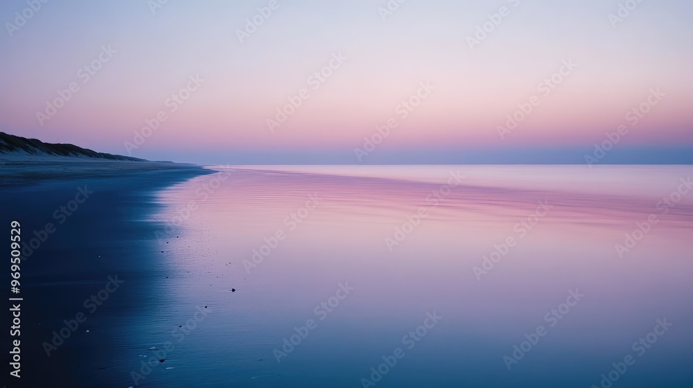 Fototapeta premium A quiet beach scene at twilight, soft pinks and blues reflecting in the calm waters.
