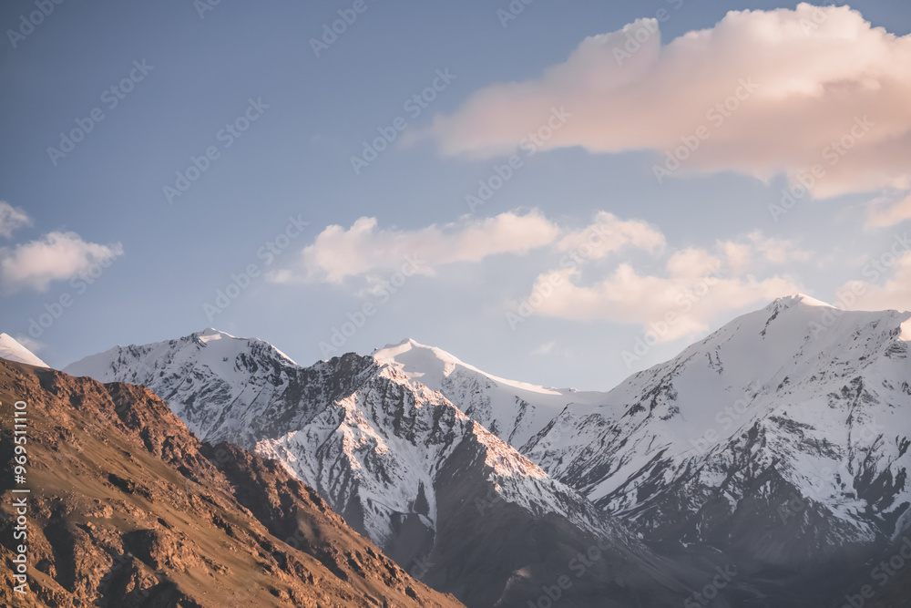 Landscape of the peaks of the mountains of the Wakhan Corridor with rocky mountain peaks with snow and glaciers in Tajikistan in the Pamirs, in the evening at sunset, minimalist landscape Landscape of the peaks of the mountains of the Wakhan Corridor with rocky mountain peaks with snow and glaciers in Tajikistan in the Pamirs, in the evening at sunset, minimalist landscape