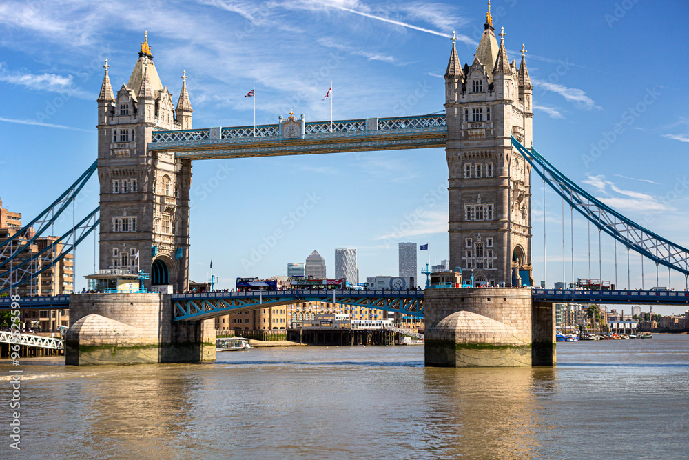 Obraz premium Historische Brücke Tower Bridge mit Doppeltürmen über den Fluss Themse unter einem klaren Himmel, umgeben von Stadtansicht, London, Vereinigte Königreich Großbritannien