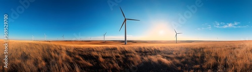 Panoramic view of wind turbines in a vast, golden grass field under a clear blue sky, capturing sustainable energy in a serene landscape.