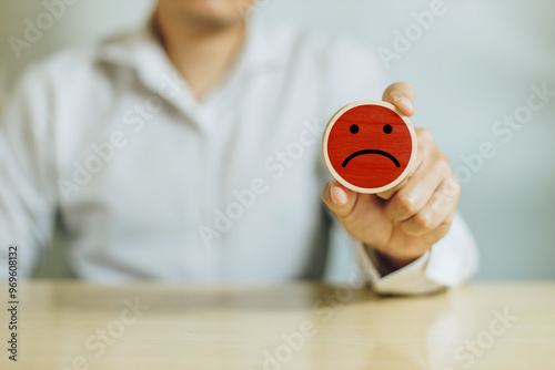 Fototapeta kuchenna Service rating, satisfaction and negative feedback. A man hold wooden cube with bad face emoticon give a one star rating indicates the lowest level of satisfaction with the service