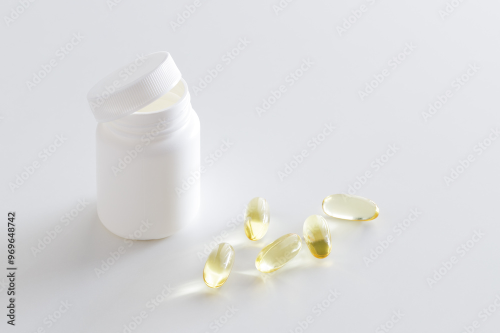 Soft gels pills with Omega-3 oil spilling out of pill bottle close-up. Vitamin D, multivitamins, Calcium. Health and Immunity concept. Soft gels pills with Omega-3 oil spilling out of pill bottle close-up. Vitamin D, multivitamins, Calcium. Health and Immunity concept.