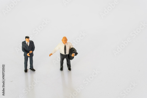 Miniature businessmen stand on white background together. Business leader, teamwork