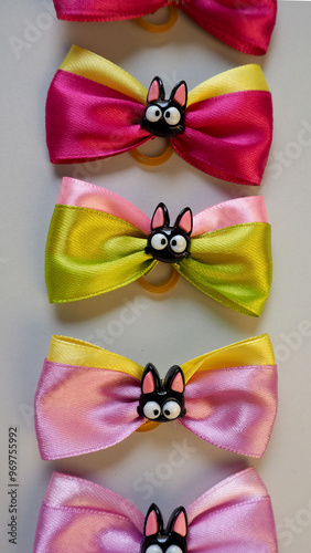 on a gray background lie green, yellow , gray, pink bows with black cats attached in the middle . Halloween pet accessories . for dods photo