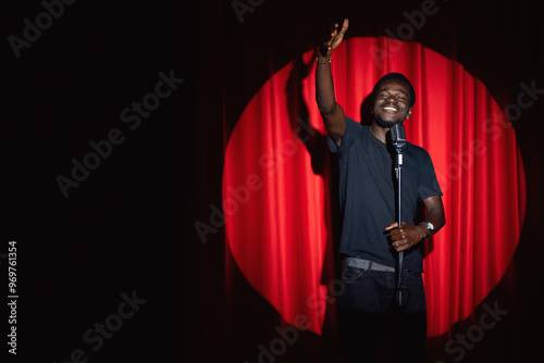 Canvas Print African american man comic with old microphone on theater stage on red curtains background