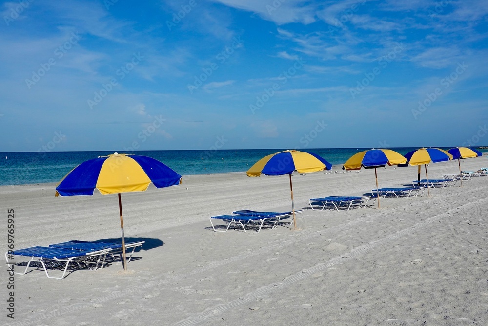 Blue and yellow beach umbrellas in the sand on a beach. Blue and yellow beach umbrellas in the sand on a beach.