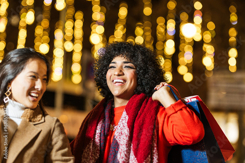 Photography Two happy women holding shopping bags enjoying christmas shopping at night