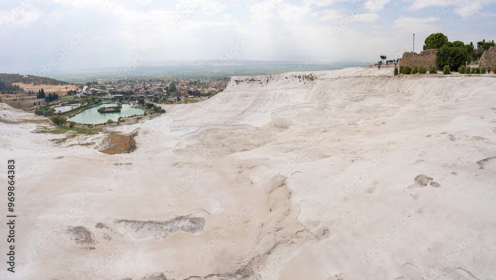 A stunning wide angle view of Pamukkale's unique geological formations and nearby town in Turkey, showcasing the natural beauty and captivating landscape.