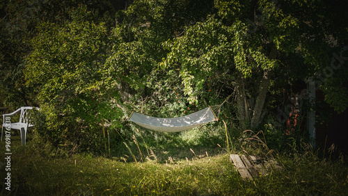 And old hammock hangs from two trees in a dreamy garden.