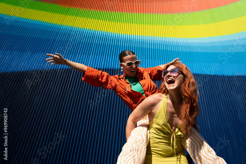 Joyful lesbian couple celebrating under colorful backdrop