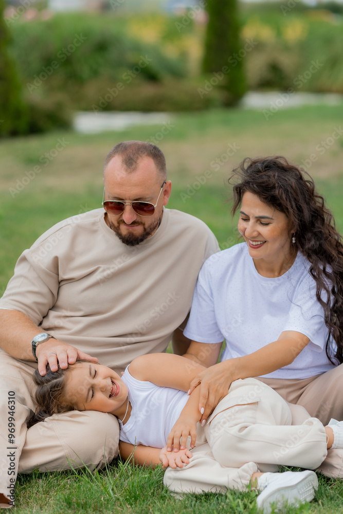 happy family is relaxing on a green lawn in the park in summer