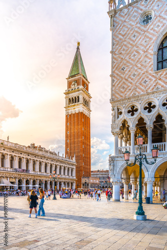 St Mark's Square bustles with visitors enjoying a sunny summer day, featuring the iconic St Mark Campanile rising majestically alongside the stunning architecture of Venice.