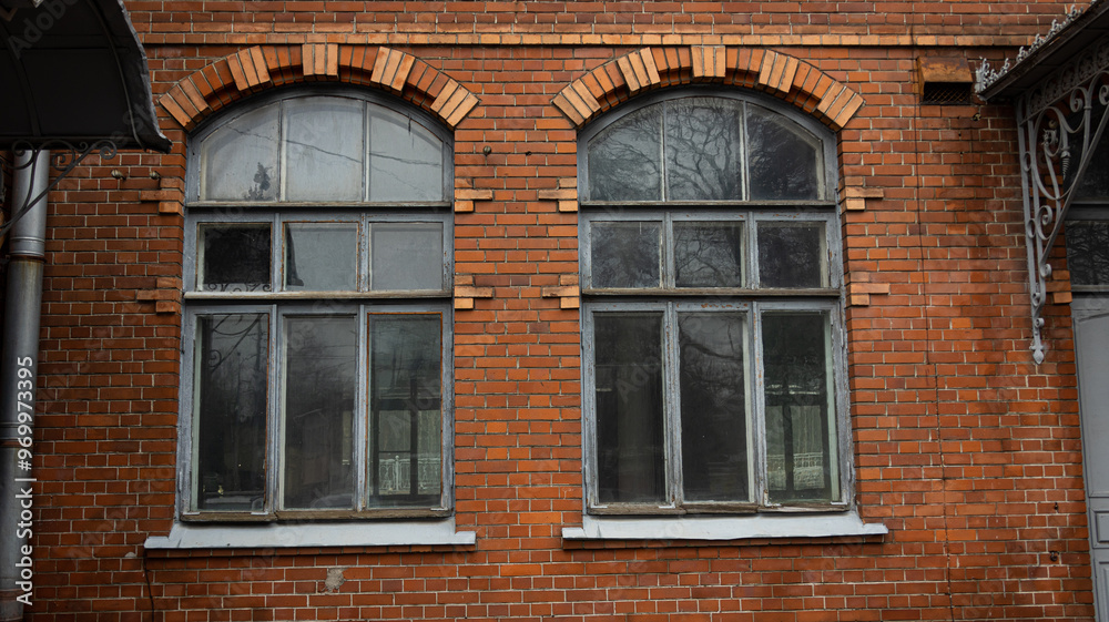 There are two elegantly arched windows located on a red brick building There are two elegantly arched windows located on a red brick building