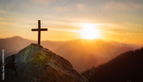 Christian cross on mountain peak at sunset.