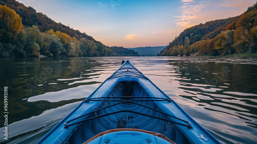 Bow of a blue kayak on the Danube River at dusk. Kayaking on a calm autumn river in the evening, viewed from the bow of the kayak. photo