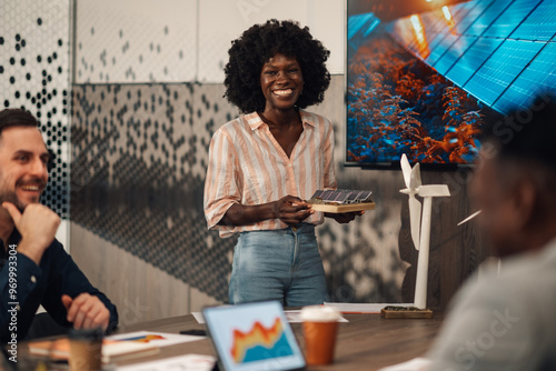 Happy diverse environmentalist with solar panel presenting at boardroom photo