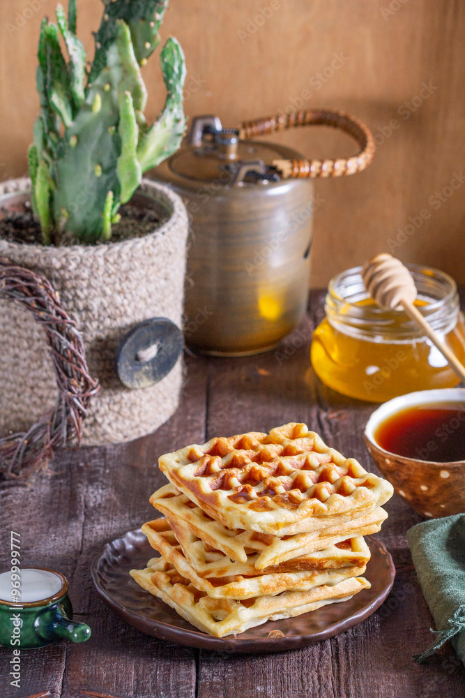 Belgian waffles served with honey, cream and sai on a wooden background. Rustic style.