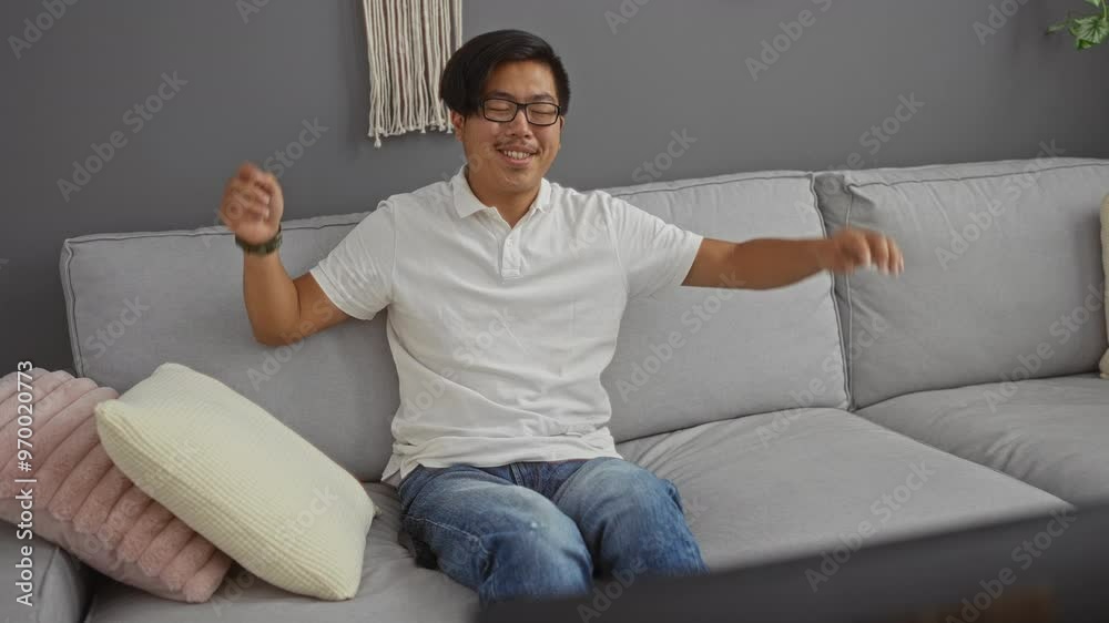Young man relaxing on a sofa in an apartment living room, showcasing an indoor lifestyle with modern interior decor Young man relaxing on a sofa in an apartment living room, showcasing an indoor lifestyle with modern interior decor