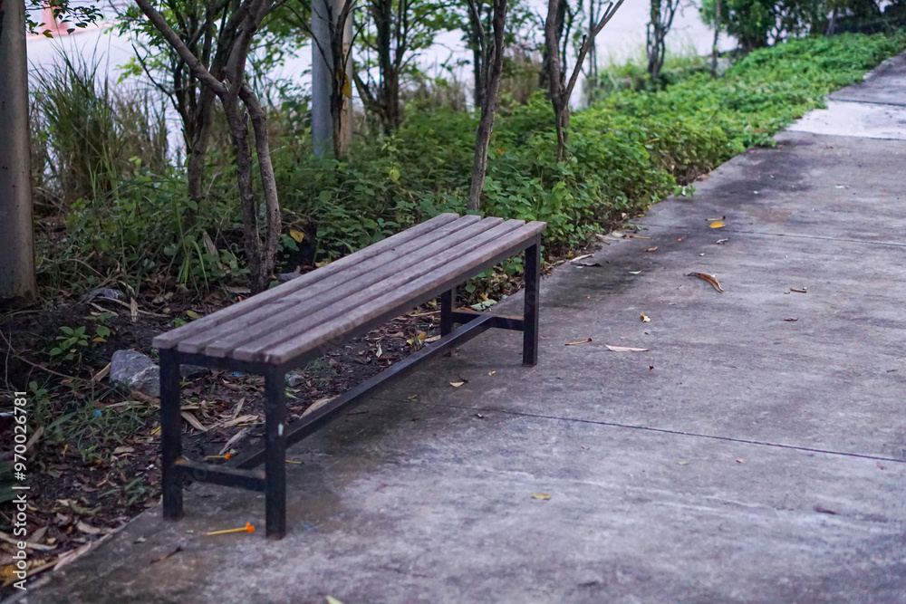 Decorative wooden bench in a city park with trees as a backdrop along the walkway. Decorative wooden bench in a city park with trees as a backdrop along the walkway.
