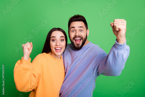 Photo of cheerful glad charming couple wear stylish clothes celebrate success isolated on green color background photo