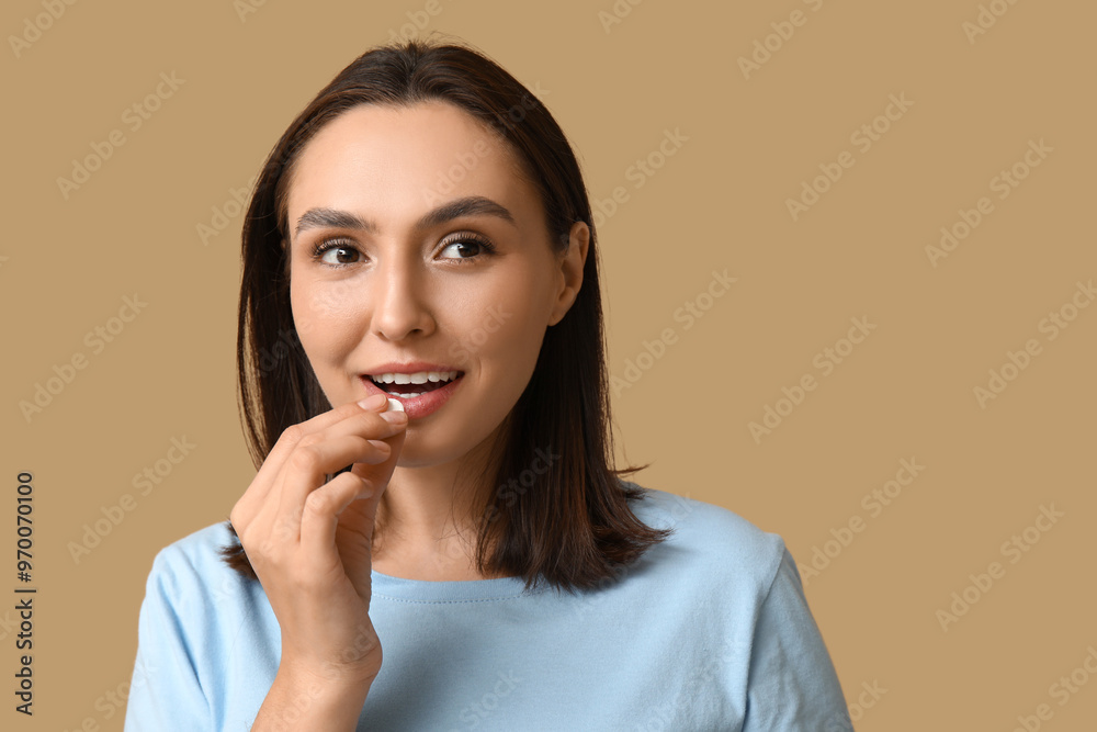 Pretty young woman taking pill on brown background Pretty young woman taking pill on brown background