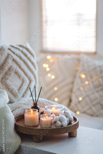 Winter home aromatherapy, cozy atmosphere. Burning aroma candles on wooden tray, knitted blanket. Christmas scent, elegant interior design. Relaxation, detention, meditation, cosiness photo