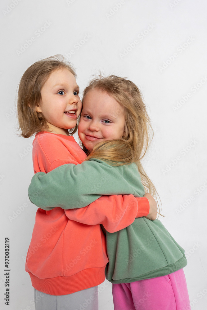 Two funny cute girls playing and having fun. Children with smiles and funny emotions on a light background. Vertical photo. High quality photo Two funny cute girls playing and having fun. Children with smiles and funny emotions on a light background. Vertical photo. High quality photo