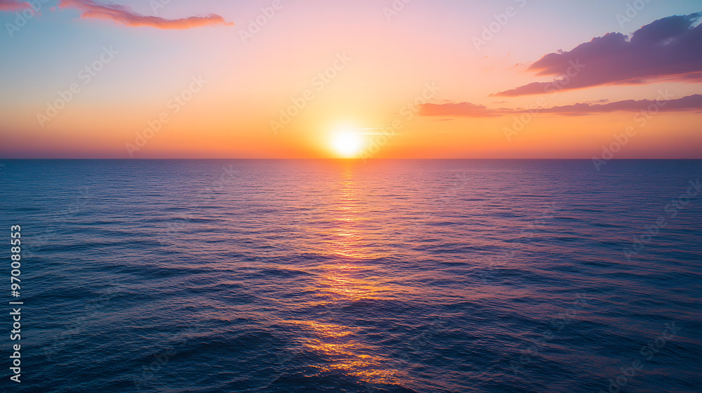Fototapeta premium A serene sunset over a calm ocean with the sun dipping below the horizon and the sky painted in shades of orange pink and purple.