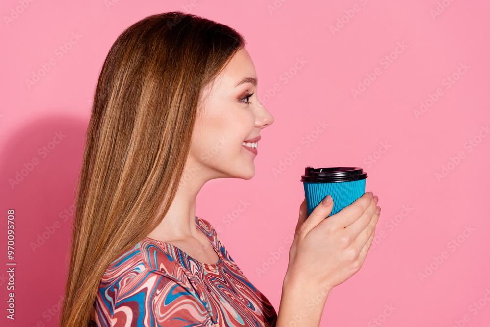 Side profile photo of positive teen with long hairstyle hold cup of latte look at offer empty space isolated on pink color background Side profile photo of positive teen with long hairstyle hold cup of latte look at offer empty space isolated on pink color background