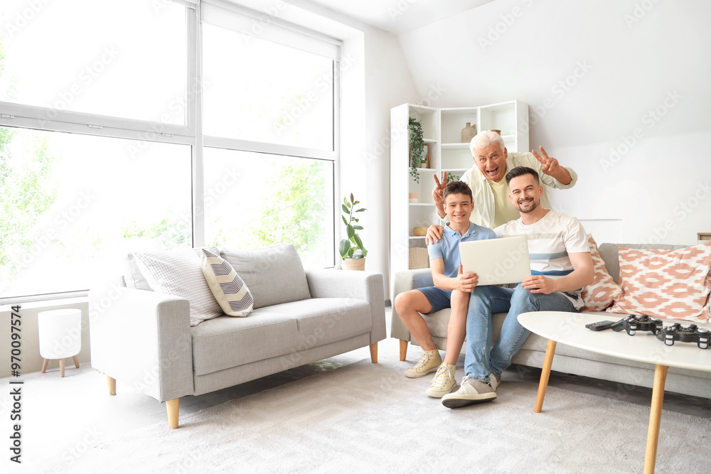 Teenage boy with his dad and grandfather using laptop on sofa at home Teenage boy with his dad and grandfather using laptop on sofa at home