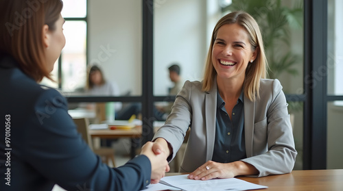 Happy mid aged business woman manager handshaking at office meeting. Smiling female hr hiring recruit at job interview, bank or insurance agent, lawyer making contract deal with client at work. 