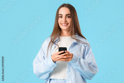 Young beautiful woman with mobile phone on blue background