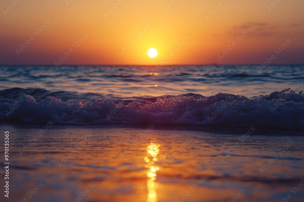Naklejka premium A mesmerizing sunset over a calm sea, where gentle waves meet the shore, creating a serene atmosphere with a golden glow, perfect for evening reflections.