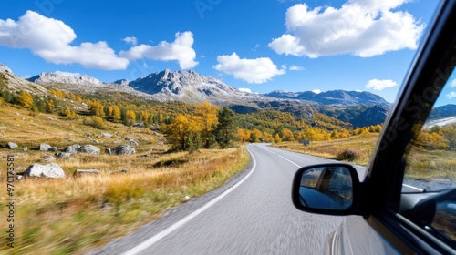 A picturesque mountain road showcases vivid autumn colors and clear blue skies. The stunning landscape is perfect for nature lovers and adventure seekers during fall. photo