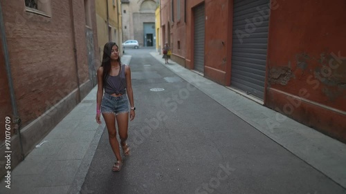 A young woman joyfully strolls through a serene and vibrant urban alleyway, enjoying life photo