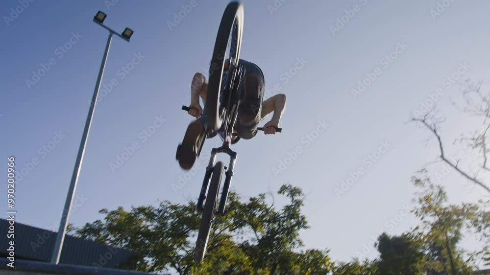 Confident person in helmet riding up ramp and making flip Confident person in helmet riding up ramp and making flip