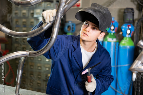 Foto Young male metallurgist working with welding machine in metallurgical workshop