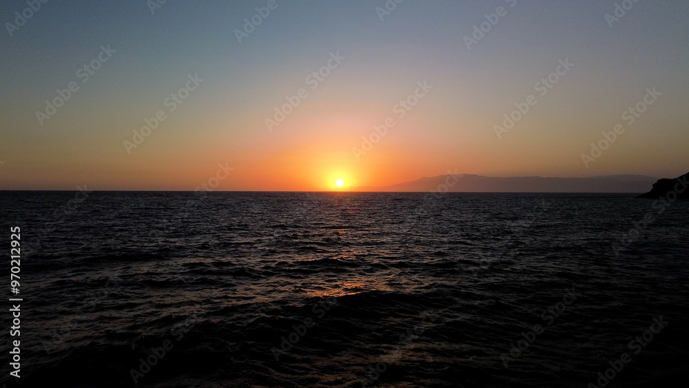 A quiet sentinel by the sea  its light shining across the vast expanse of water  surrounded by cliffs and rocky shores