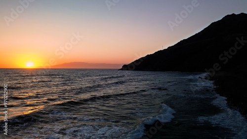 Perched high above the crashing waves the lighthouse watches over the endless blue horizon of the sea 