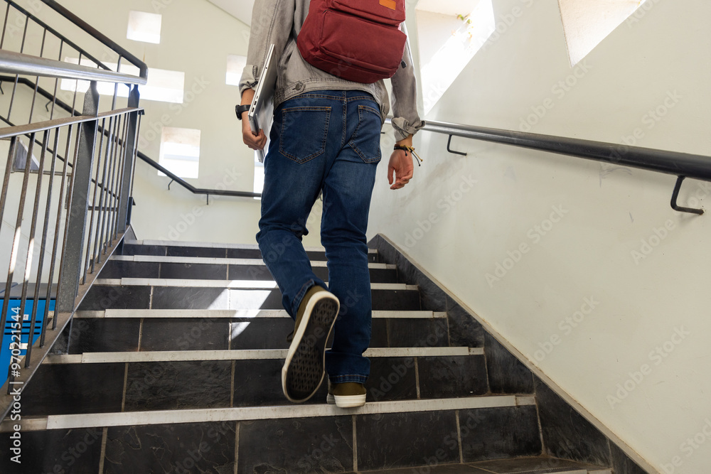 Walking up stairs, asian teenage boy with red backpack heading to class in school Walking up stairs, asian teenage boy with red backpack heading to class in school