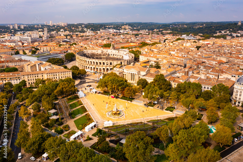 Fototapeta premium Aerial view of historical area of French city of Nimes overlooking restored antique Roman amphitheatre on sunny autumn day